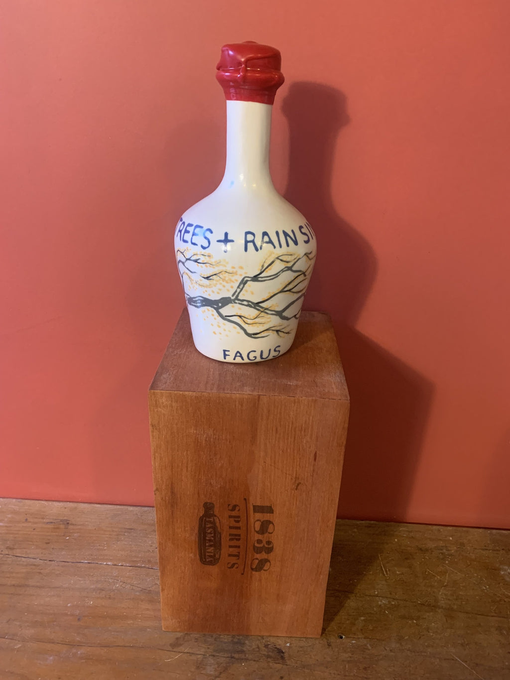 The Fagus ceramic decanter, hand-painted with golden autumn Nothofagus gunnii foliage, standing on its 1838 Spirits timber box
