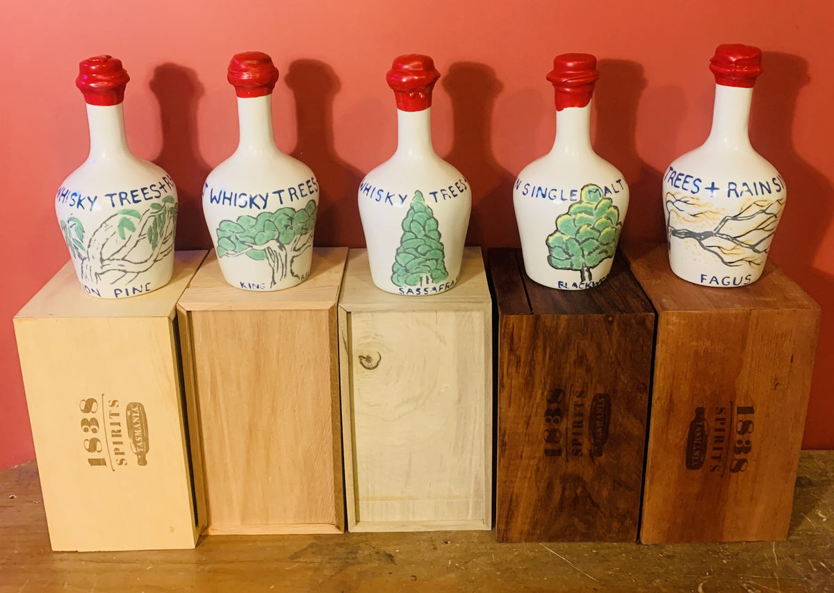 Five hand-painted Trees & Rain ceramic whisky decanters — Huon Pine, King Billy, Sassafras, Blackwood and Fagus — each on its branded 1838 Spirits timber box