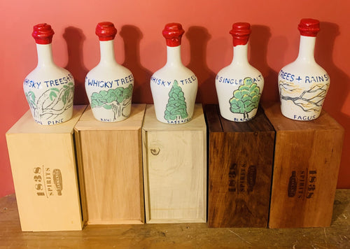 Five hand-painted Trees & Rain ceramic whisky decanters — Huon Pine, King Billy, Sassafras, Blackwood and Fagus — each on its branded 1838 Spirits timber box